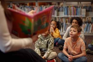 a group of children sit for a book reading